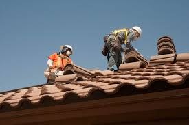 Two men from a roofing company are meticulously replacing a residential roof.